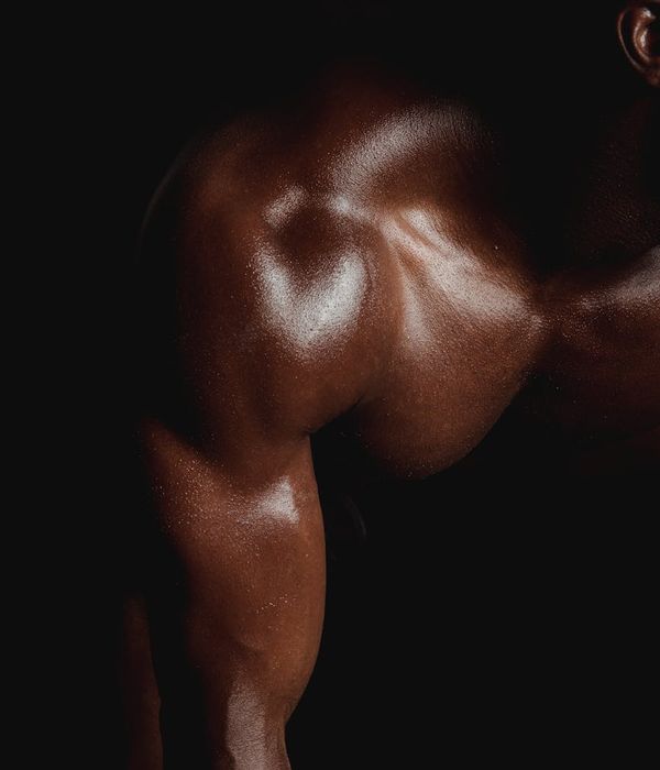 Man performing a strength exercise in a dark gym with cyan light accents.